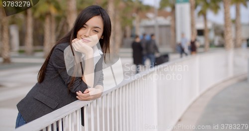 Image of Young thoughtful woman leaning on a railing