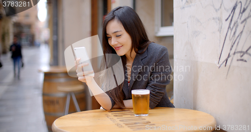 Image of Smiling young woman relaxing with a beer