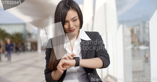 Image of Young woman checking her wristwatch for the time