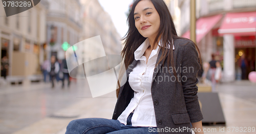 Image of Woman sitting on a bench in town waiting