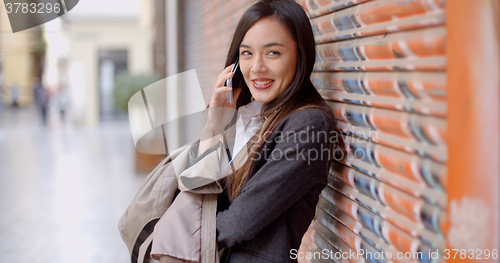 Image of Young woman talking on her mobile in town