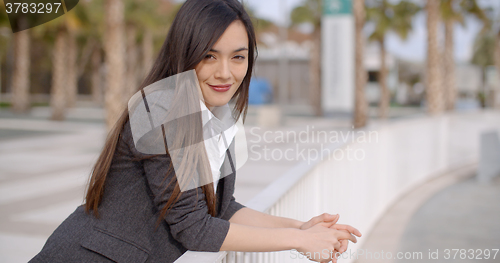 Image of Relaxed thoughtful young woman leaning on railings