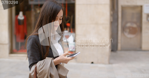 Image of Young woman standing checking her mobile