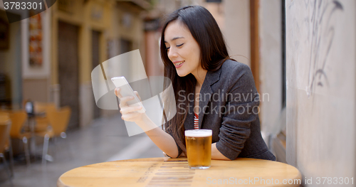 Image of Smiling young woman relaxing with a beer