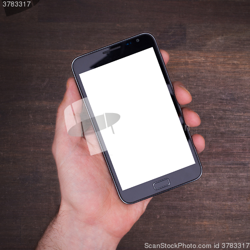 Image of Hand with smart phone on wooden table
