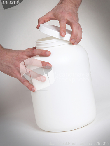 Image of Bodybuilding and Sports themehands holding a plastic jar with a 