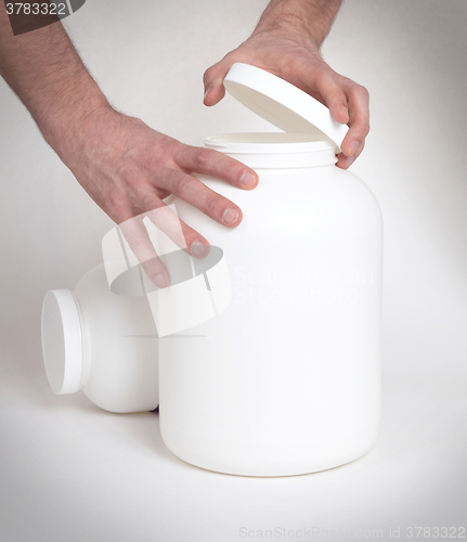 Image of Bodybuilding and Sports themehands holding a plastic jar with a 