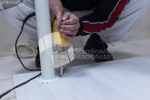 Image of repairman working with drilling machine