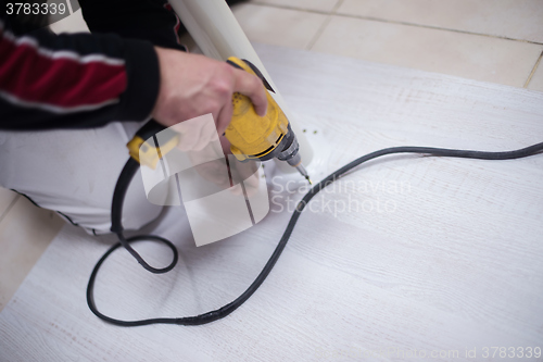 Image of repairman working with drilling machine