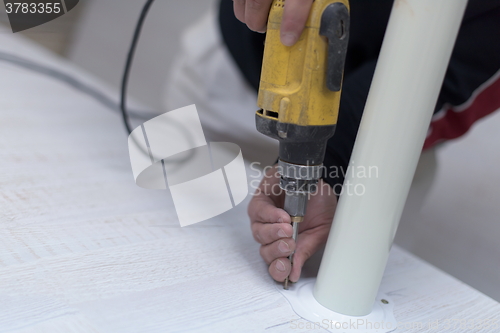 Image of repairman working with drilling machine