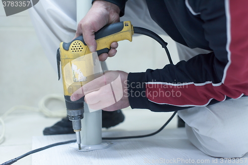 Image of repairman working with drilling machine