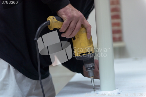 Image of repairman working with drilling machine