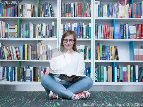 Image of student girl reading book in library