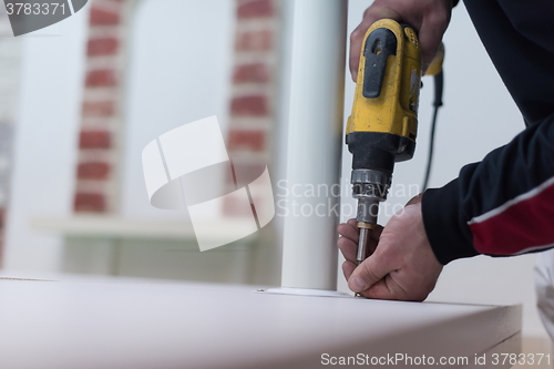 Image of repairman working with drilling machine