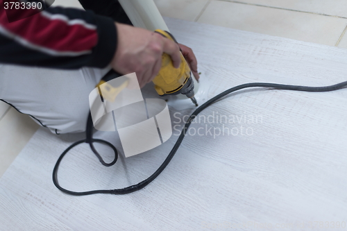 Image of repairman working with drilling machine