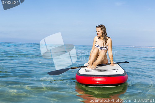 Image of Woman sitting over a paddle surfboard