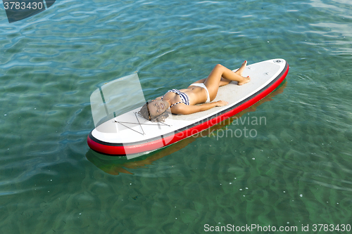 Image of Woman relaxing over a paddle surfboard