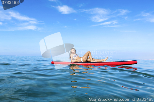 Image of Woman relaxing over a paddle surfboard