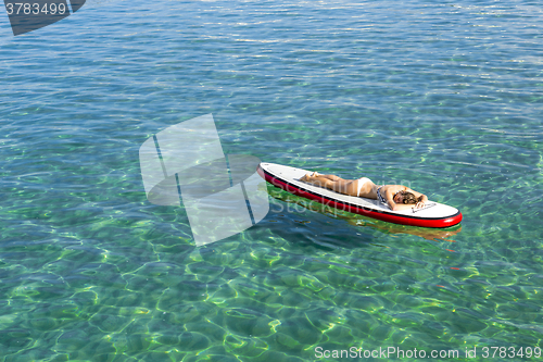 Image of Woman relaxing over a paddle surfboard