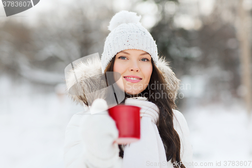 Image of happy young woman with tea cup outdoors in winter