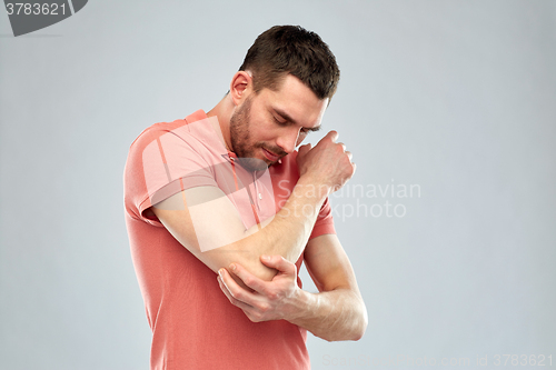 Image of unhappy man suffering from pain in hand