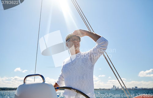 Image of senior man at helm on boat or yacht sailing in sea