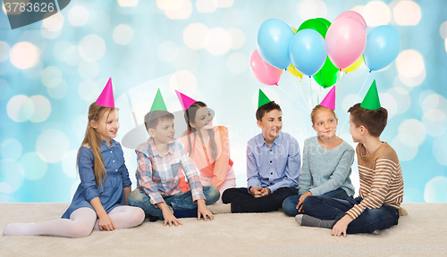 Image of happy smiling children in party hats on birthday