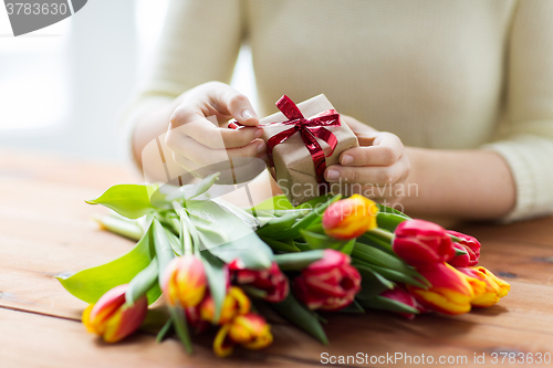 Image of close up of woman with gift box and tulip flowers