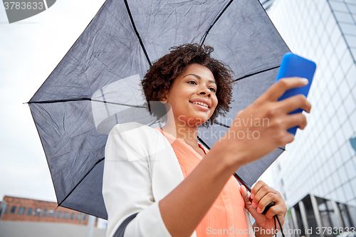 Image of businesswoman with umbrella texting on smartphone