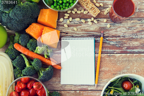 Image of close up of ripe vegetables and notebook on table