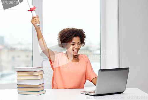 Image of happy african woman with laptop, books and diploma