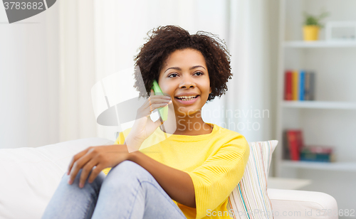Image of happy african woman with smartphone at home