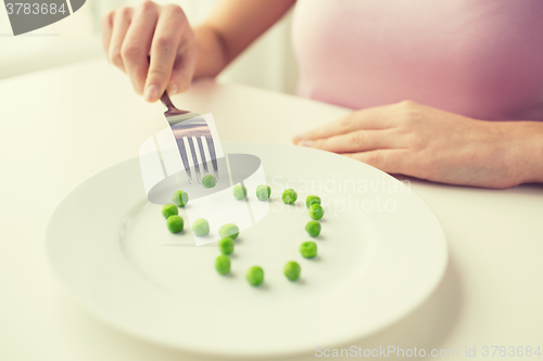 Image of close up of woman with fork eating peas