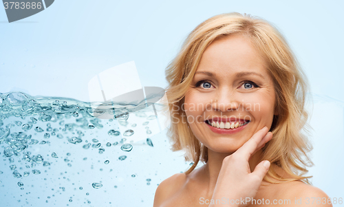 Image of smiling woman with bare shoulders touching face