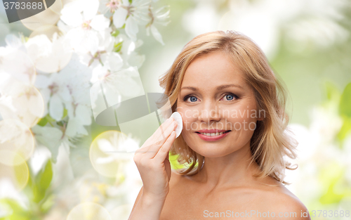 Image of happy woman cleaning face with cotton pad