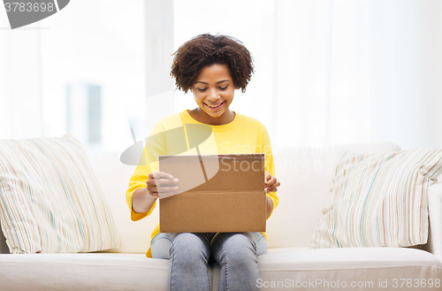 Image of happy african young woman with parcel box at home