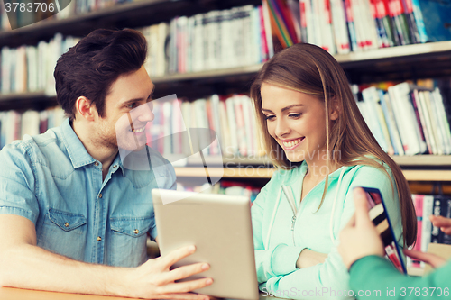 Image of happy students with tablet pc in library