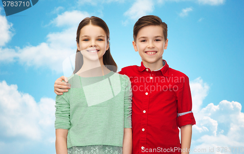 Image of happy boy and girl hugging over blue sky