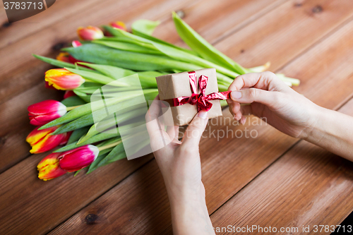 Image of close up of woman with gift box and tulip flowers