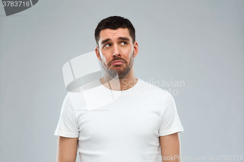 Image of unhappy young man over gray background