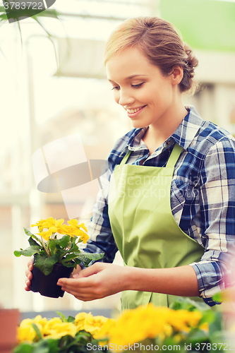 Image of happy woman holding flowers in greenhouse