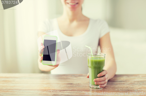 Image of close up of woman with smartphone and green juice