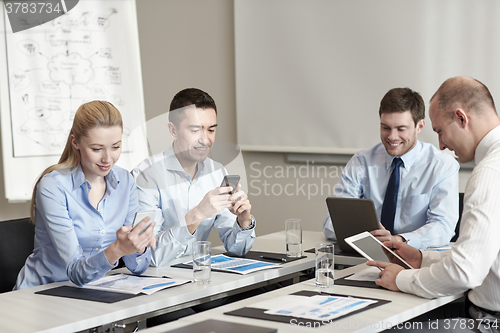 Image of smiling business people with gadgets in office