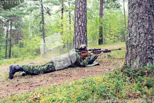 Image of young soldier or hunter with gun in forest