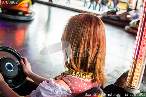 Image of Beautiful girl in an electric bumper car in amusement park