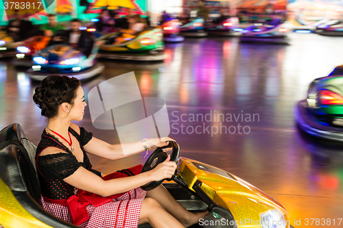 Image of Beautiful girl in an electric bumper car at amusement park