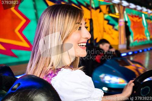 Image of Beautiful girl in an electric bumper car at amusement park