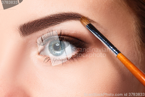 Image of Beautiful female eyes with bright blue make-up and brush