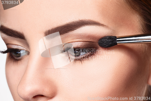 Image of Beautiful female eyes with bright blue make-up and brush