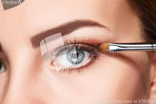 Image of Beautiful female eyes with bright blue make-up and brush